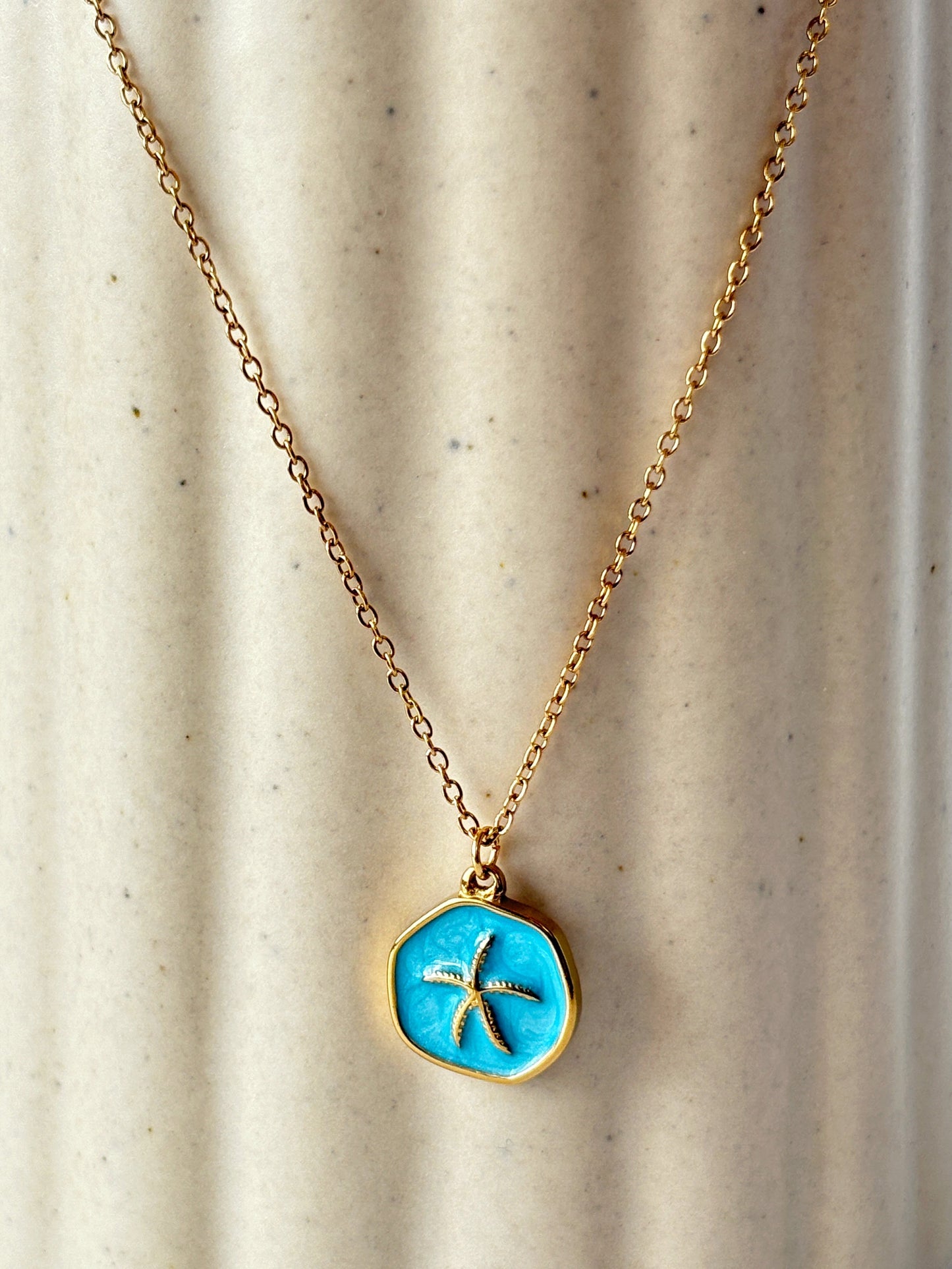 Necklace with a blue pendant featuring a starfish design on a beige background