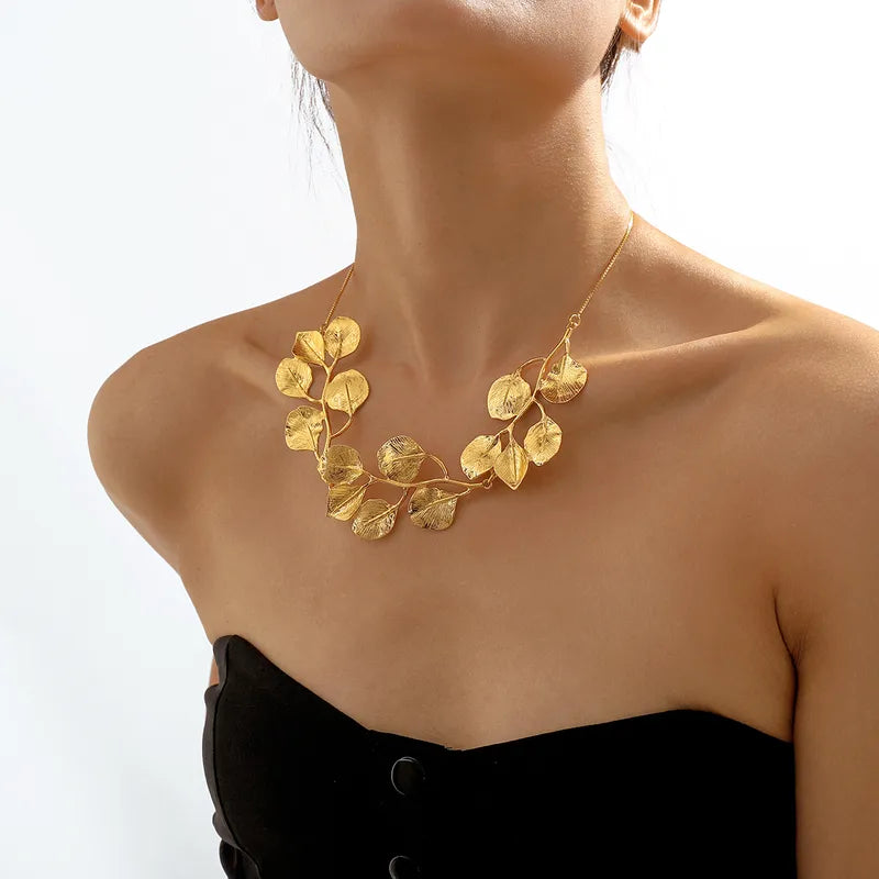 Gold leaf necklace worn by a model on a white background