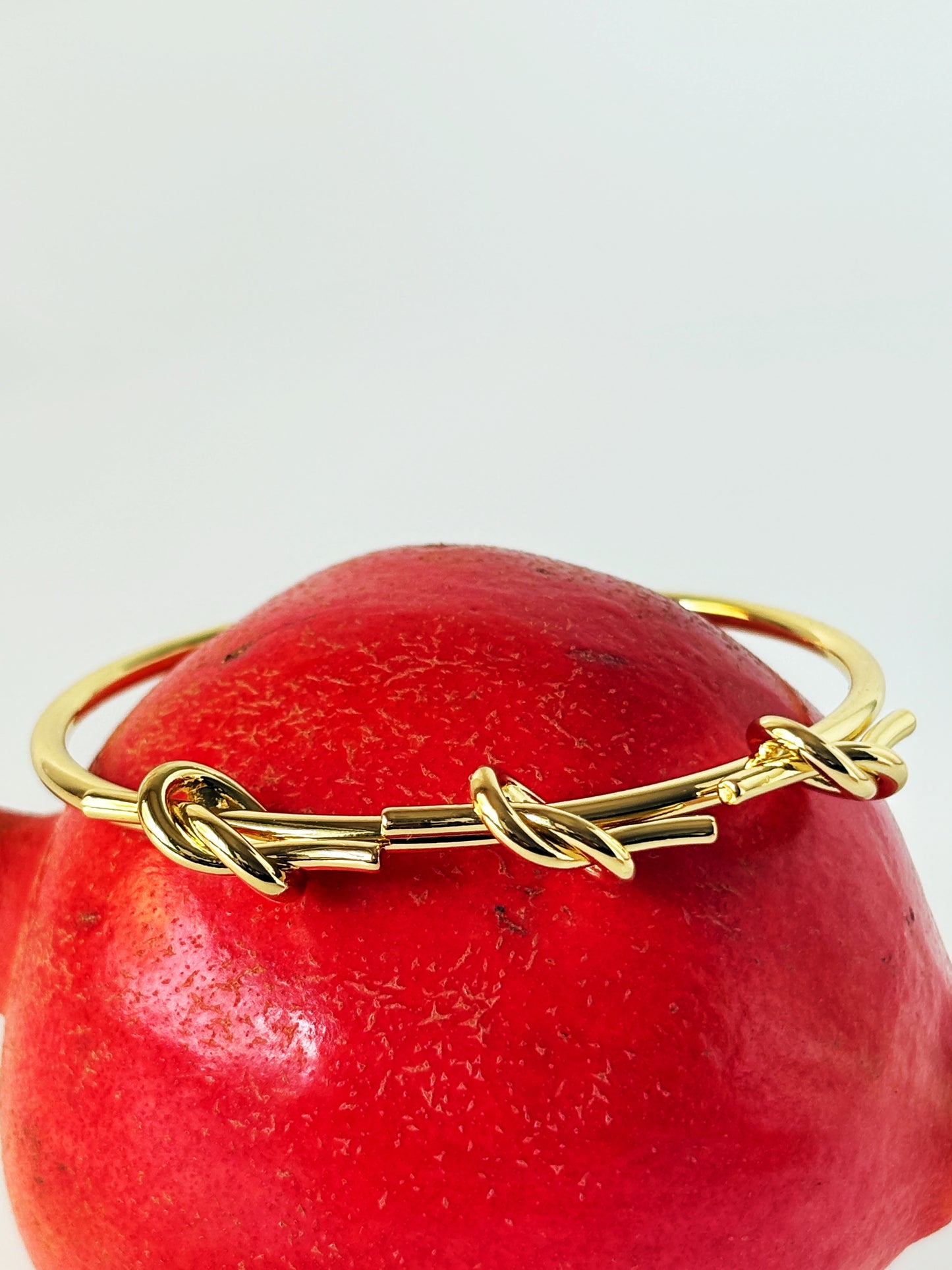 Gold bracelet on a red apple with a white background