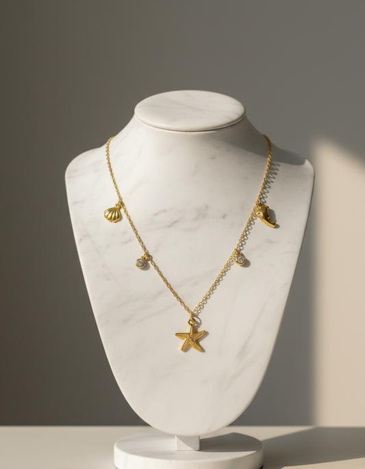 Gold necklace with star pendant on a marble bust against a gray background
