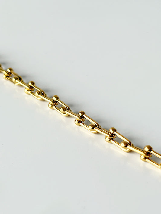 Gold chain bracelet on a light gray background