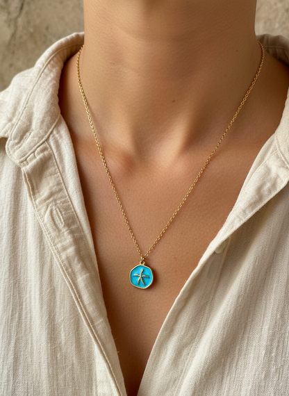 Necklace with a blue pendant worn by a person in a light-colored shirt.