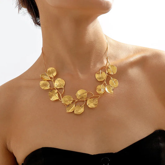 Gold leaf necklace worn by a person on a neutral background