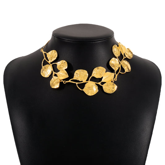 Gold leaf necklace on a black mannequin bust with a white background