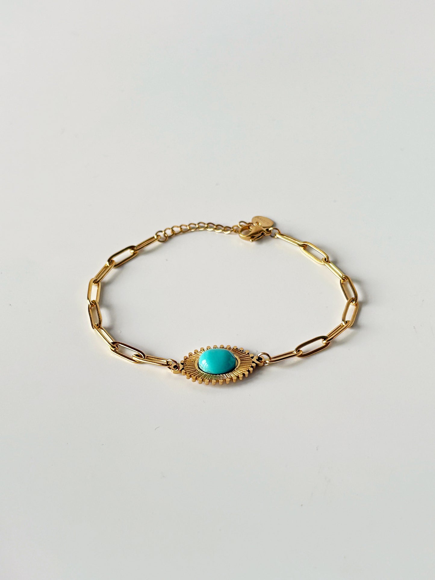 Gold bracelet with a turquoise stone on a light gray background