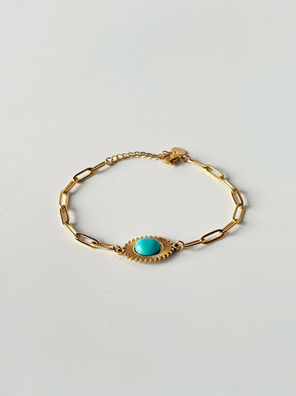 Gold bracelet with a turquoise stone on a light gray background