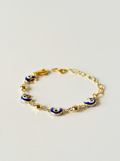 Gold bracelet with blue evil eye charms on a light gray background