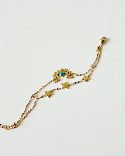Gold bracelet with star and eye-shaped charms on a light background