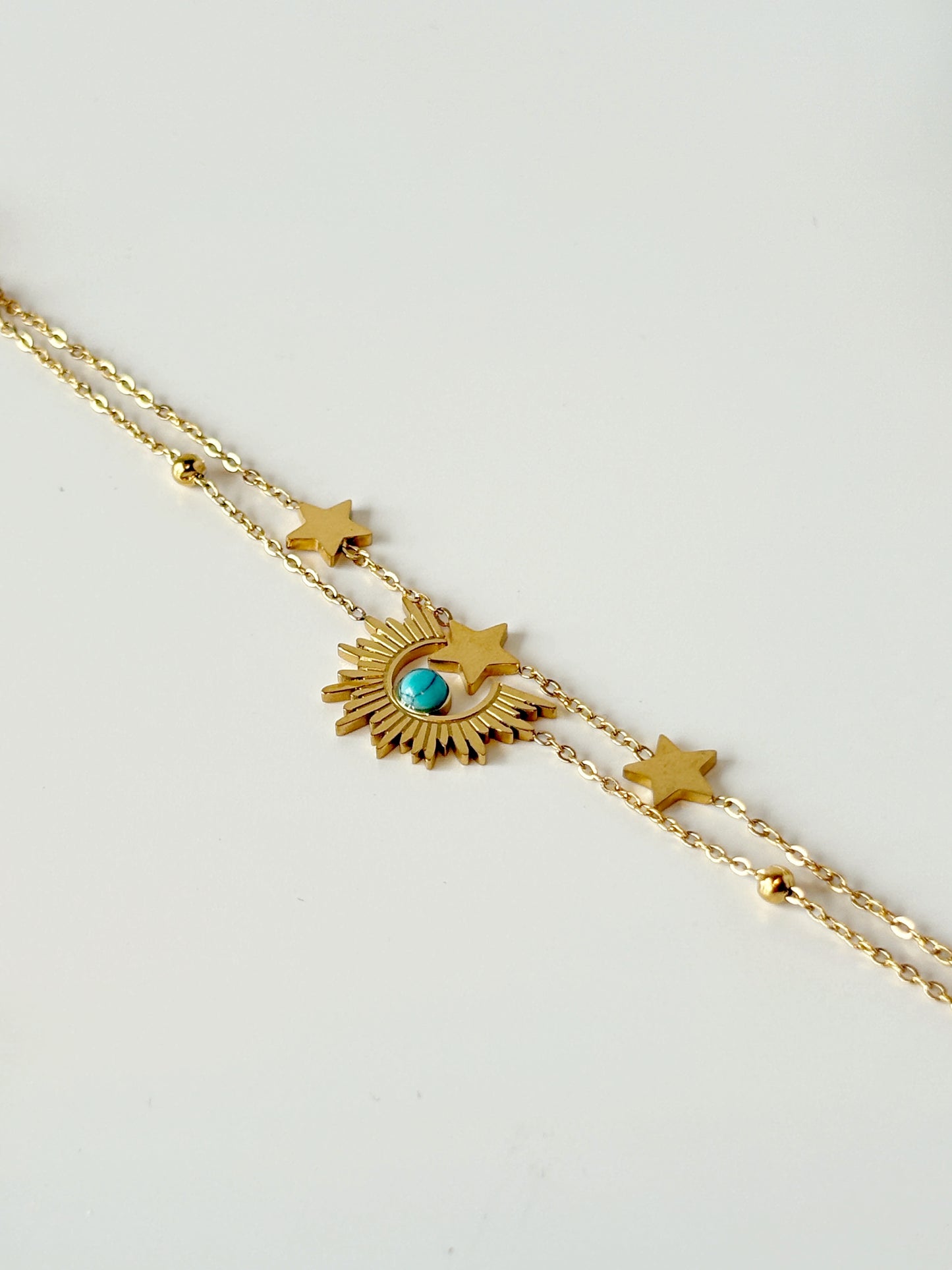 Gold necklace with star and eye-shaped pendant on a light gray background