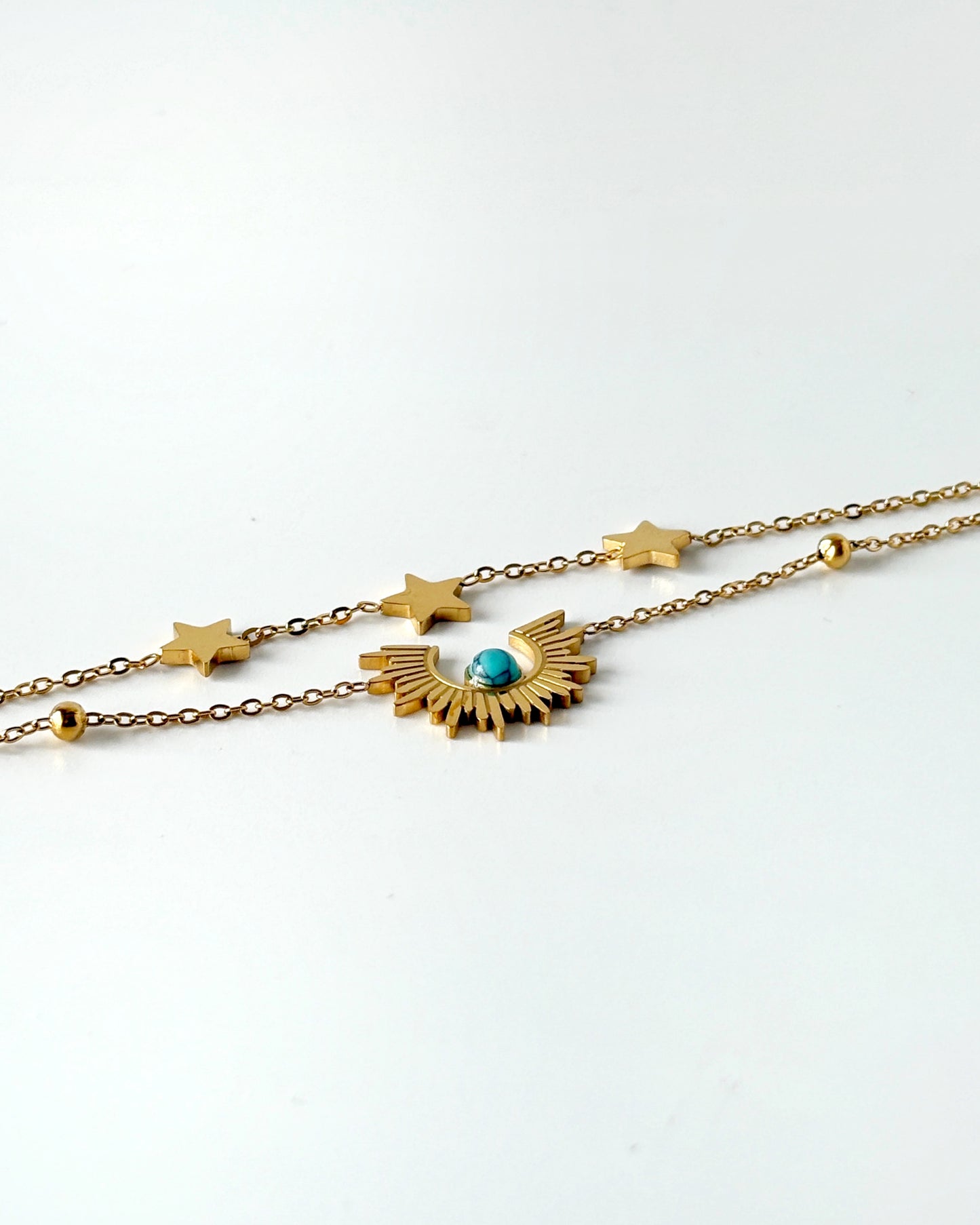 Gold necklace with star and moon design on a white background