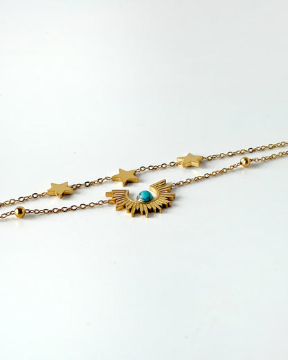 Gold necklace with star and moon design on a white background