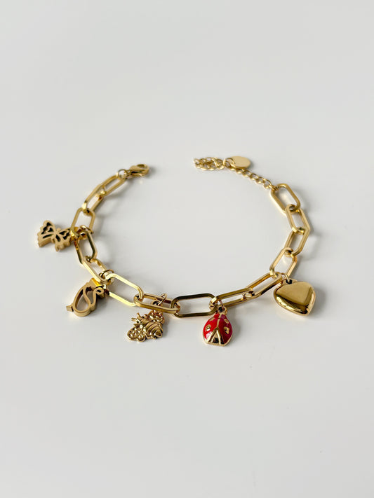 Gold bracelet with various charms on a light gray background