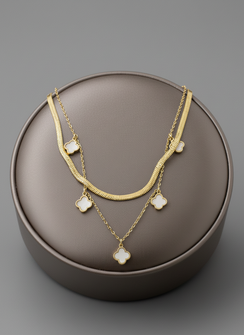 Gold necklace with clover charms on a brown round box