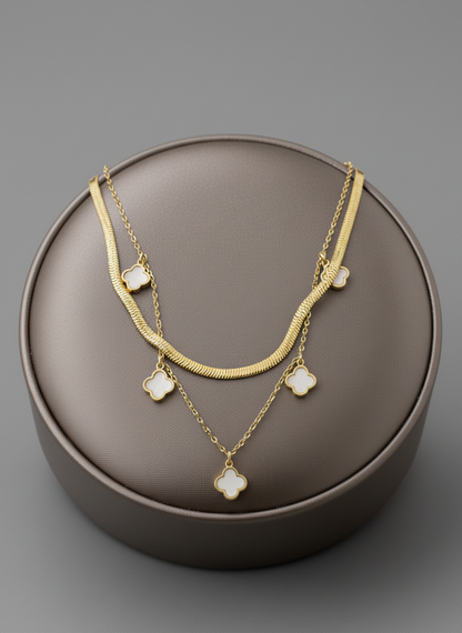 Gold necklace with clover charms on a brown round box