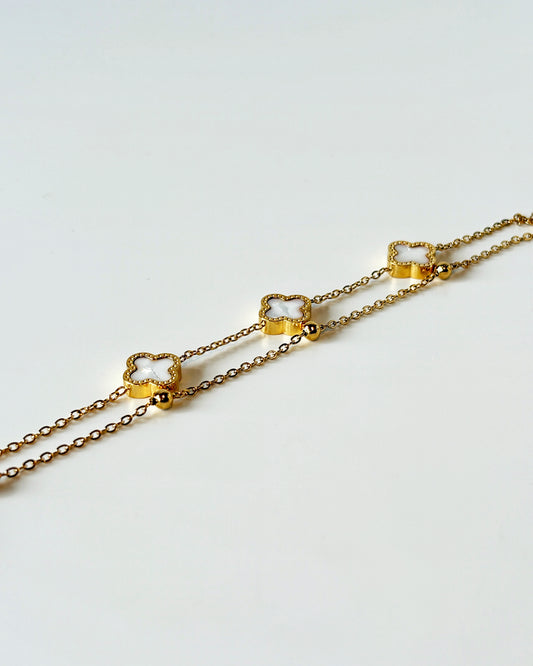 Gold chain clover necklace on a light gray background