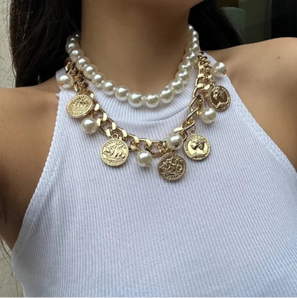Pearl necklace with gold coins worn by a person in a white top.