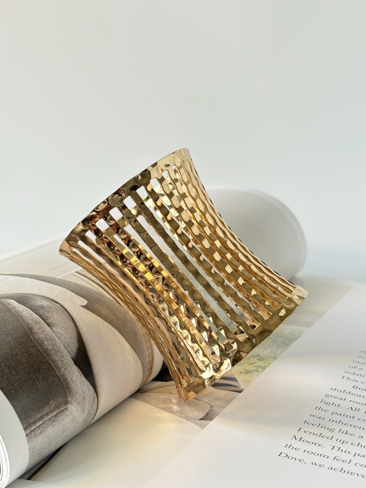 Gold bracelet cuff on an open book with a white background