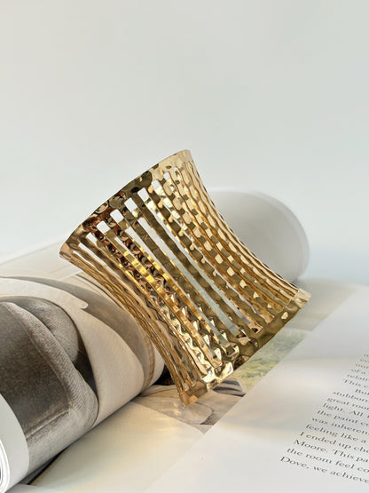 Gold bracelet cuff on an open book with a white background