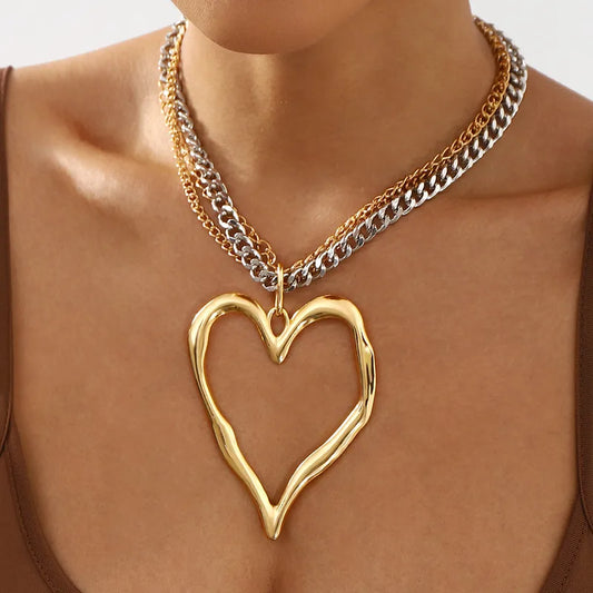 Gold heart-shaped pendant necklace on a person with a neutral background