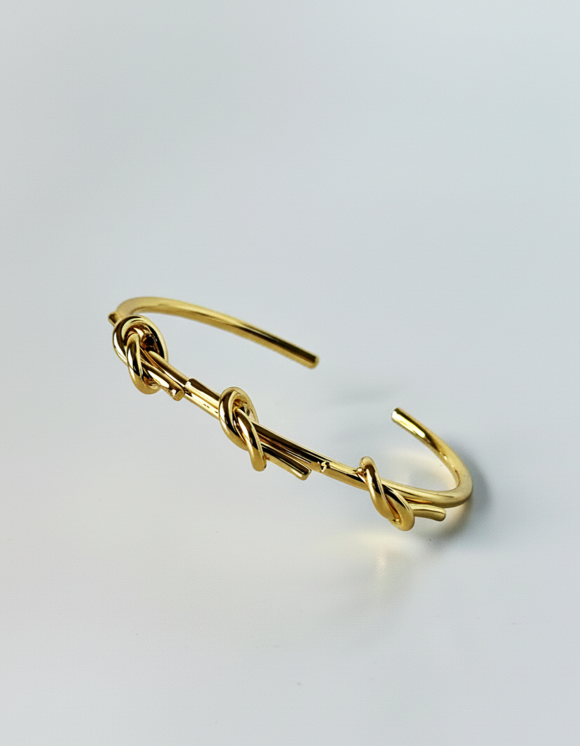 Gold bracelet with a hook closure on a light gray background