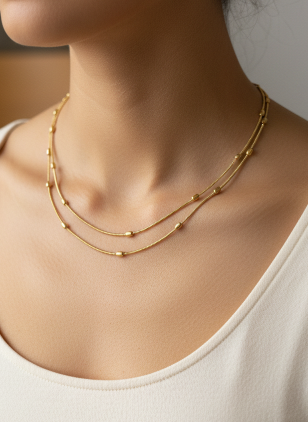 Woman wearing a gold necklace with a neutral background