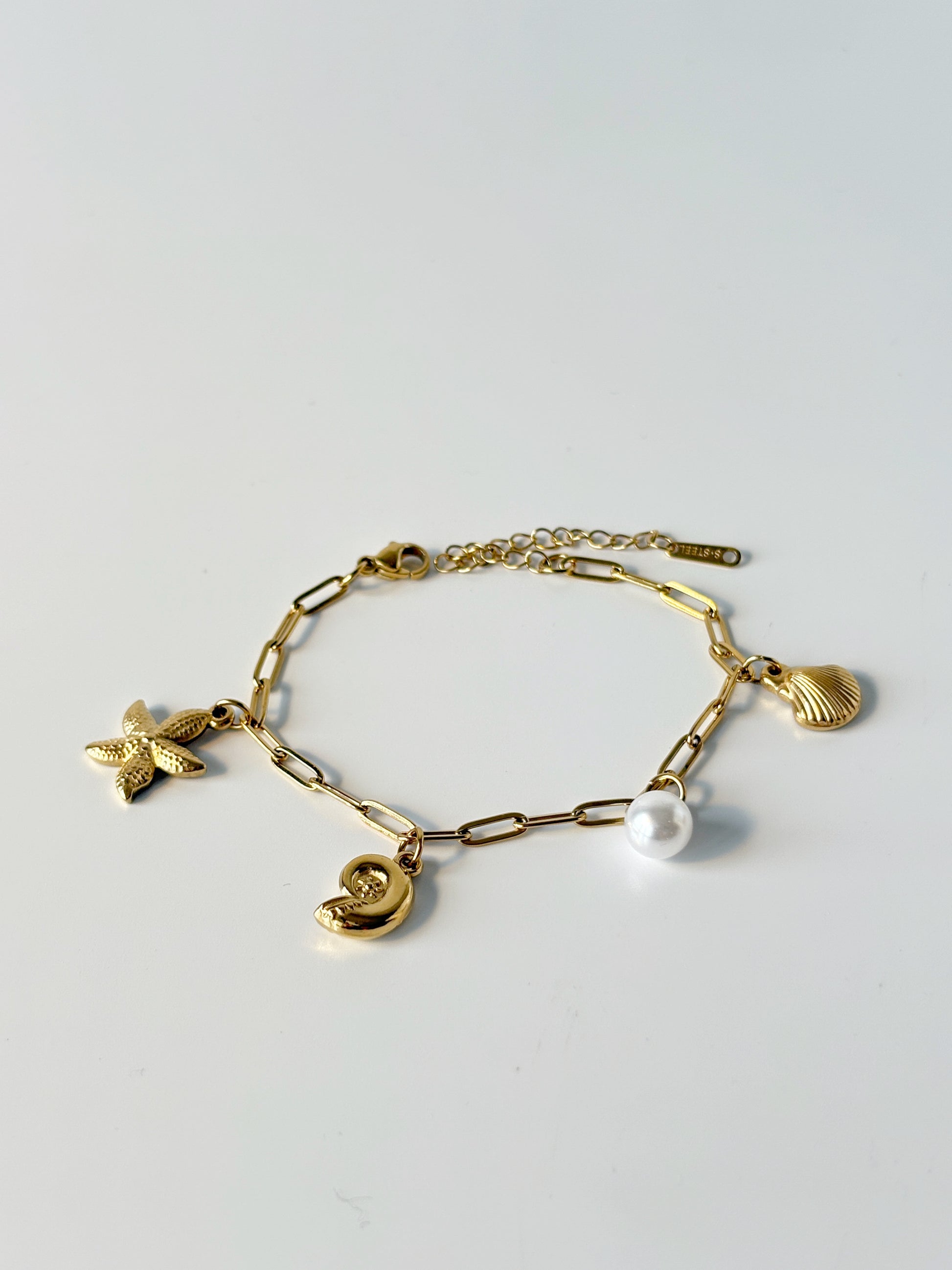 Gold bracelet with various charms on a light gray background