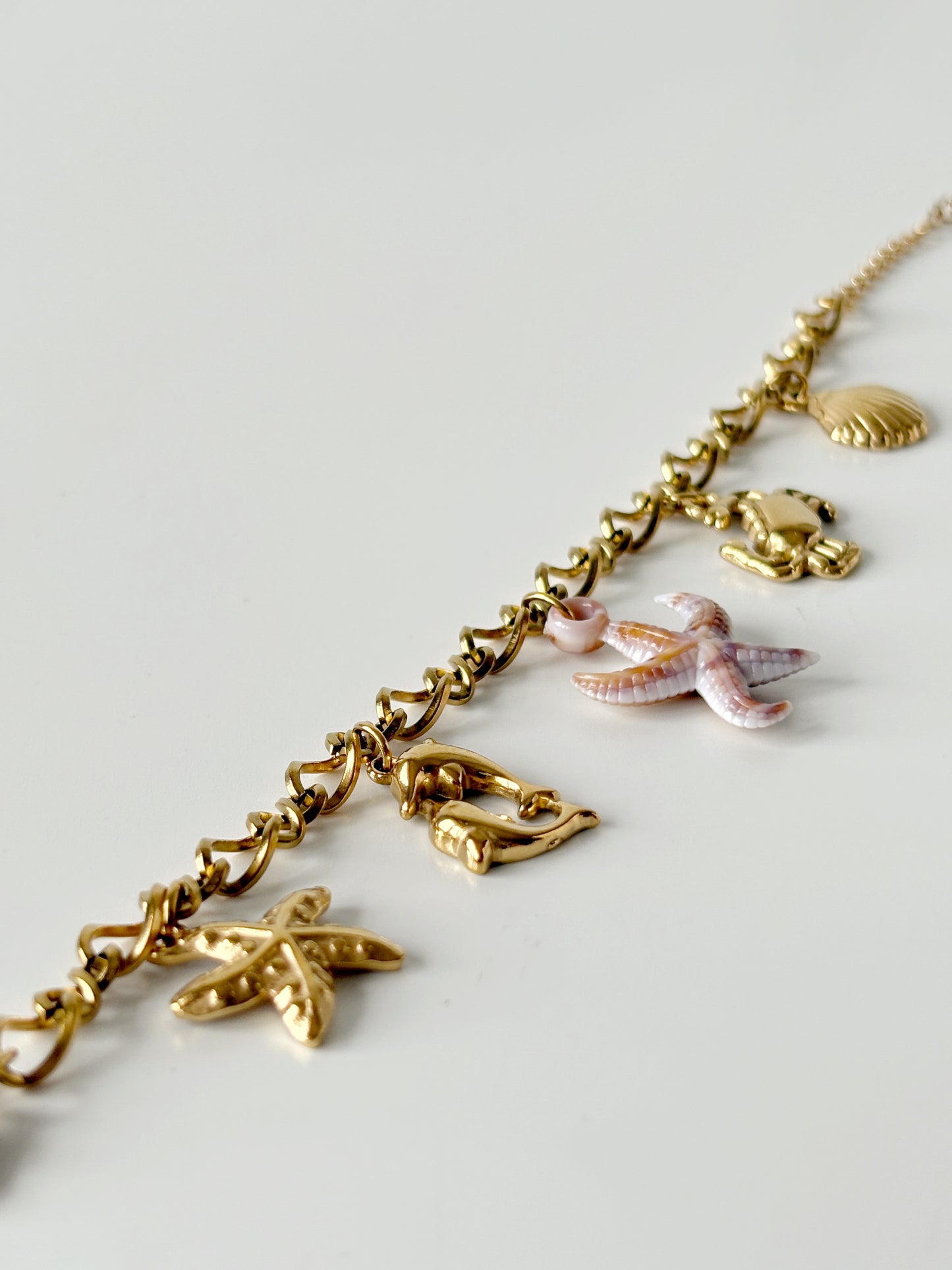 Gold necklace with various charms on a light gray background
