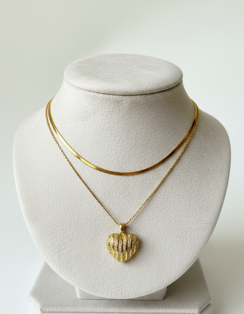 Gold necklace with a heart-shaped pendant on a mannequin bust against a white background
