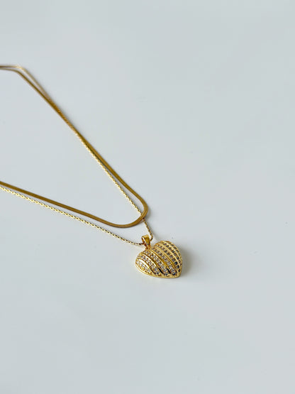 Gold necklace with a textured pendant on a light gray background