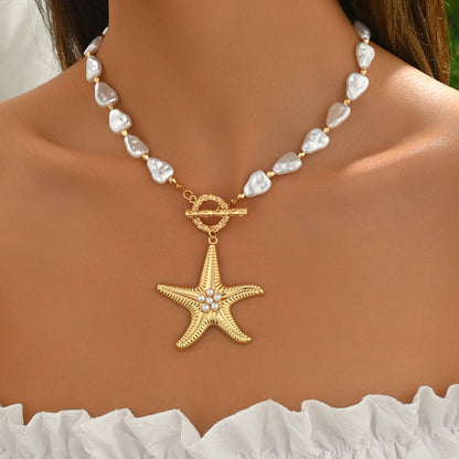 Pearl necklace with a gold starfish pendant on a person wearing a white top.