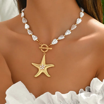 Gold starfish pendant necklace on a person wearing a white top