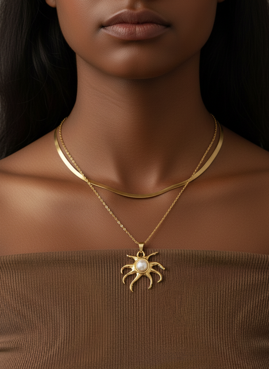 Woman wearing a gold necklace with a sun-shaped pendant on a dark background