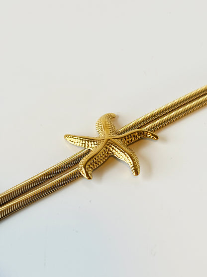 Gold starfish-shaped bracelet on a white background