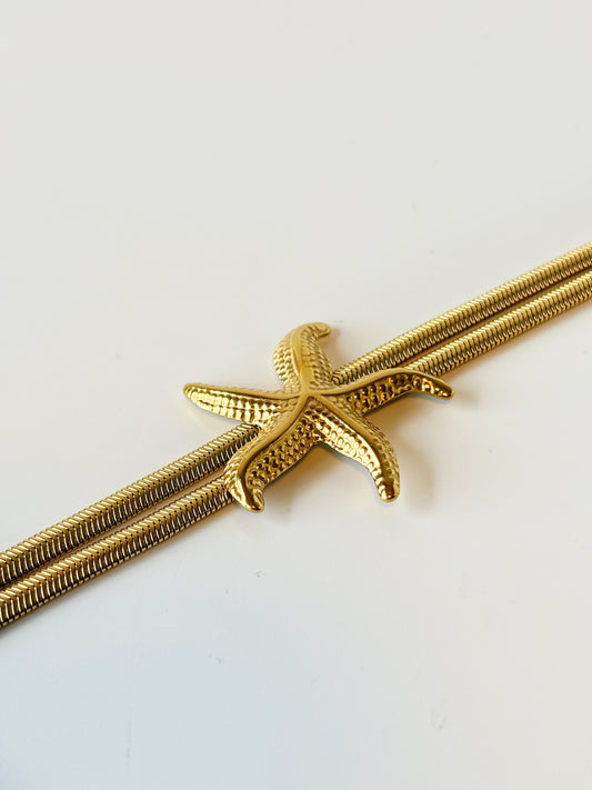 Gold starfish-shaped bracelet on a white background