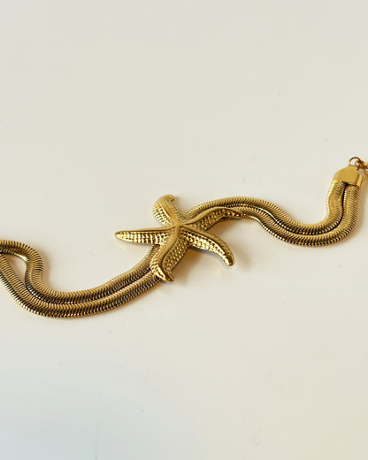 Gold starfish bracelet on a light beige background