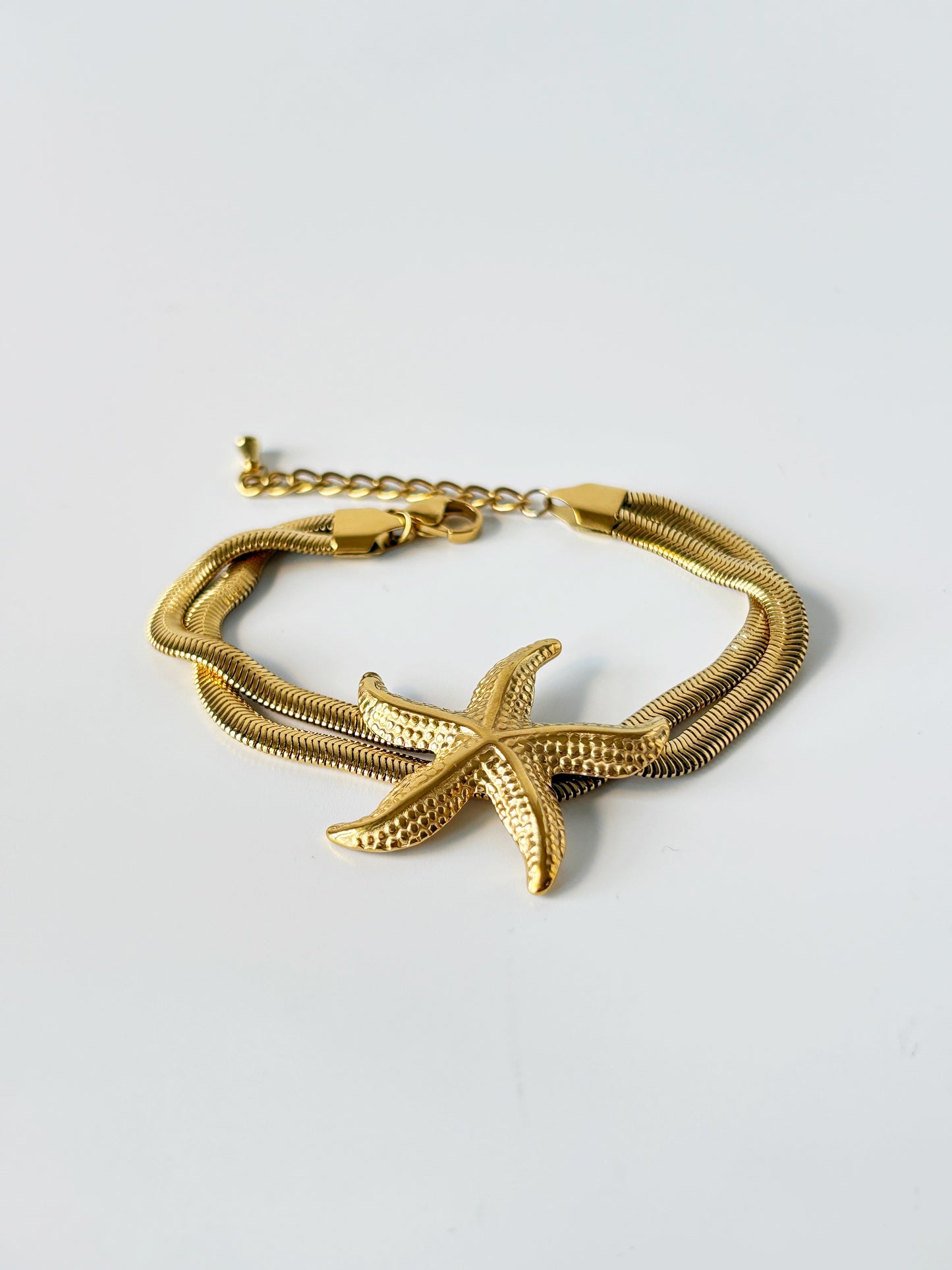Gold bracelet with starfish design on a light gray background
