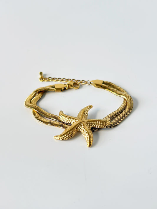 Gold bracelet with starfish design on a light gray background