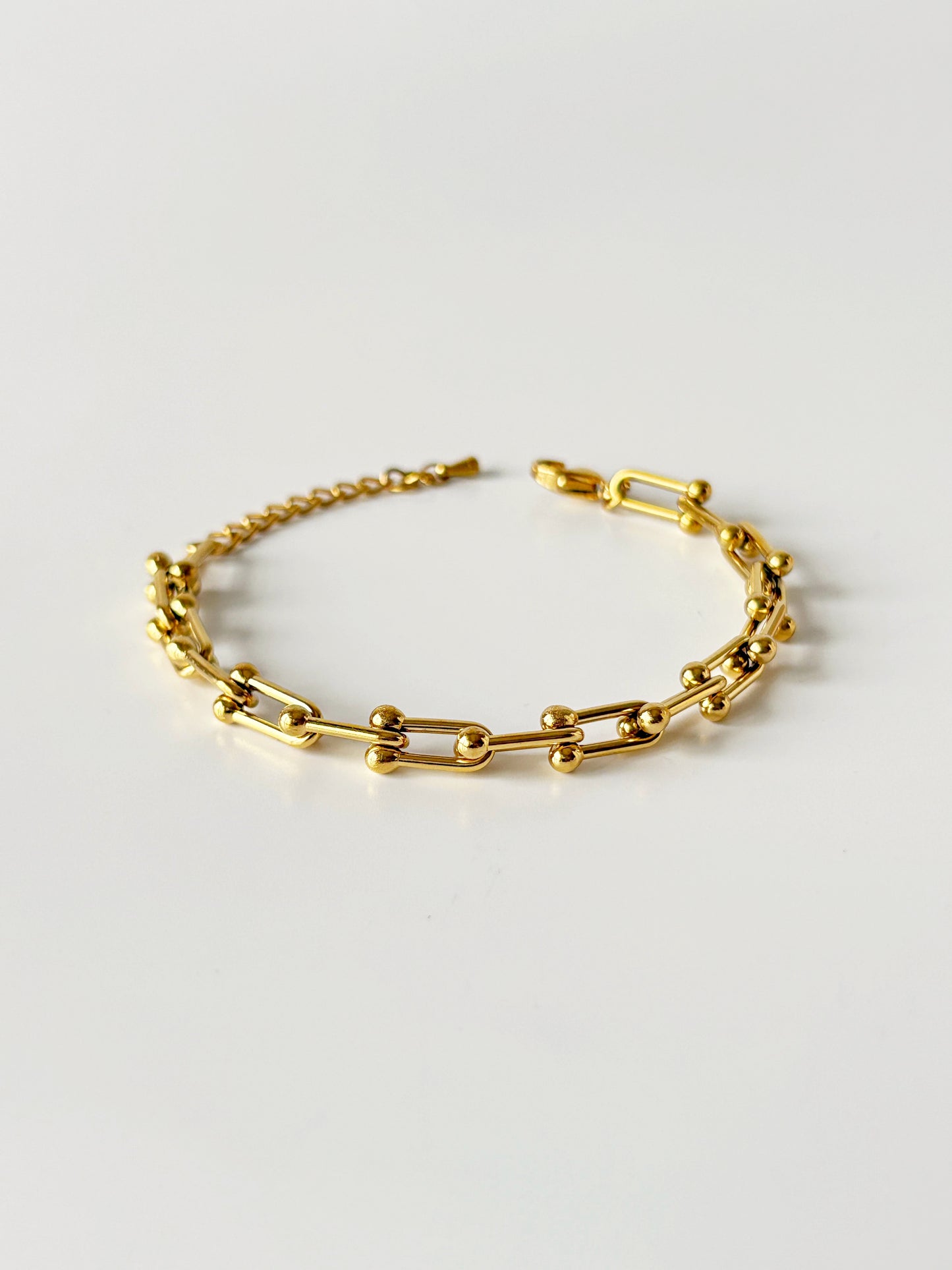 Gold chain bracelet on a light gray background