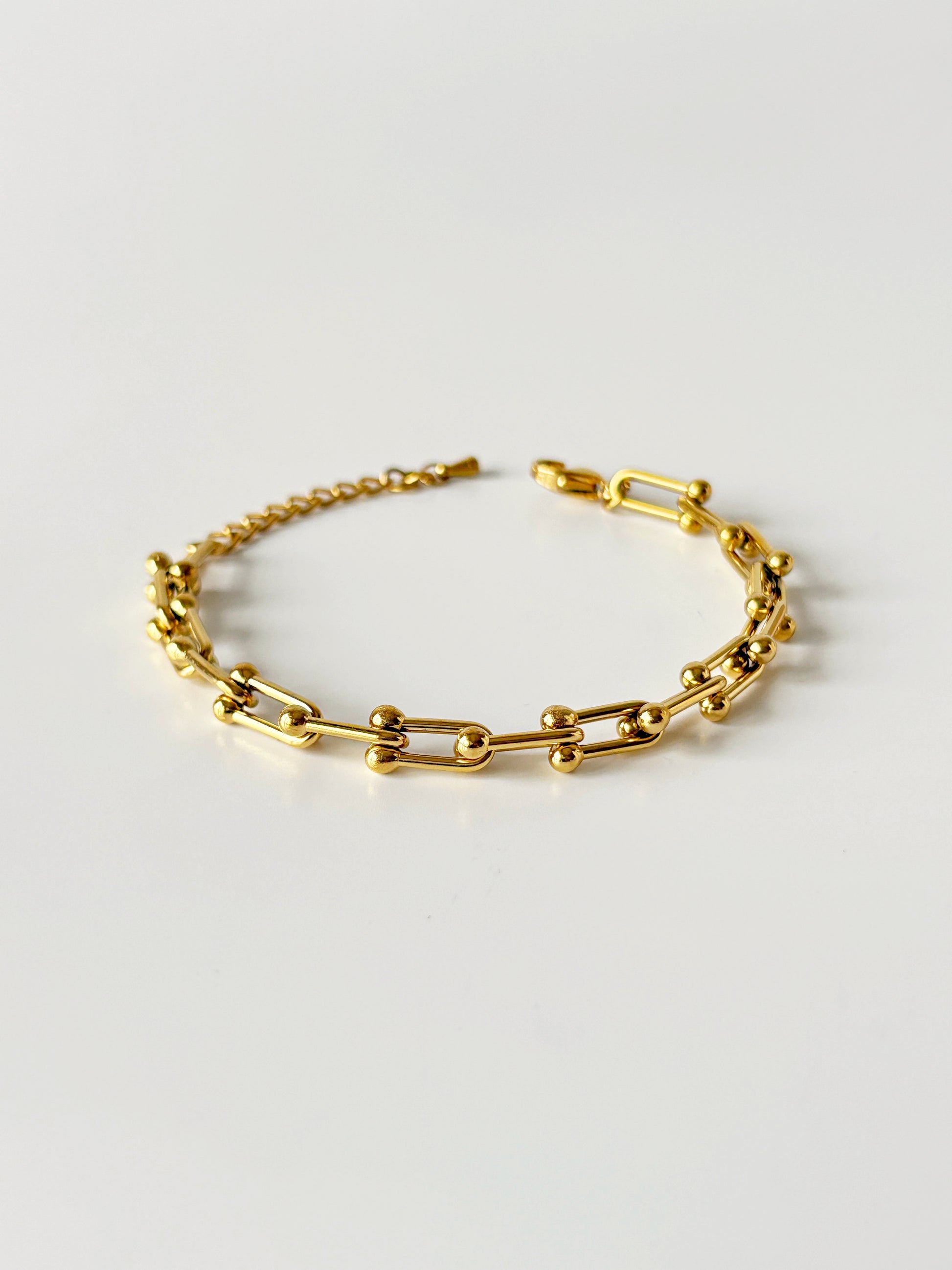 Gold chain bracelet on a light gray background