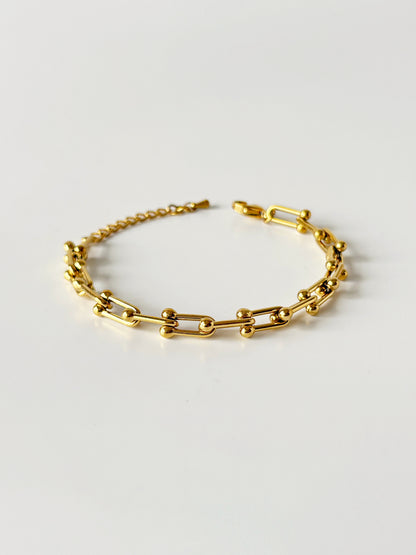 Gold chain bracelet on a light gray background