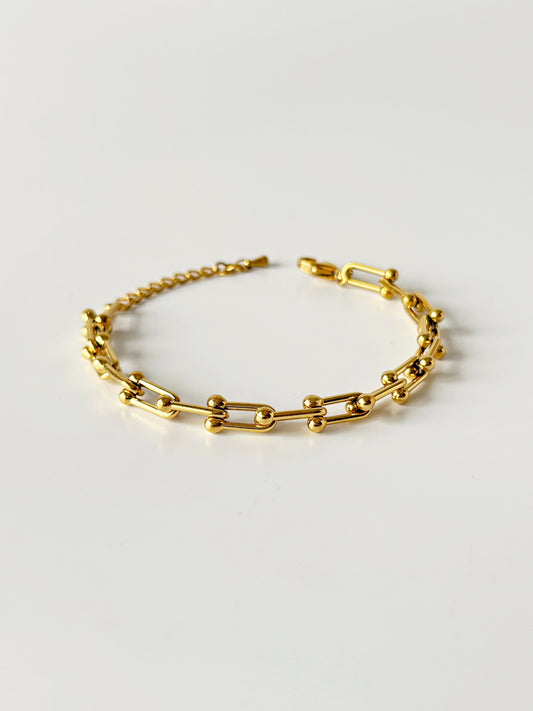 Gold chain bracelet on a light gray background