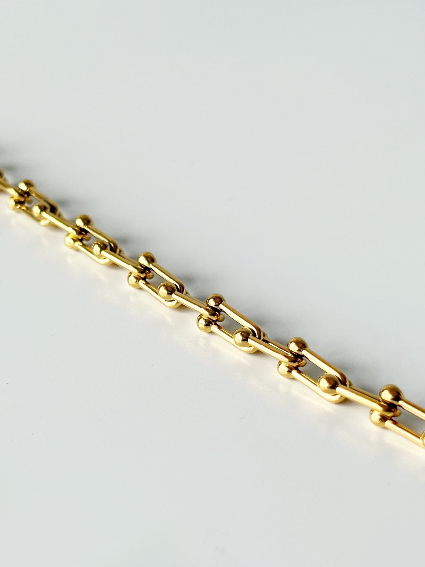 Gold chain bracelet on a light gray background