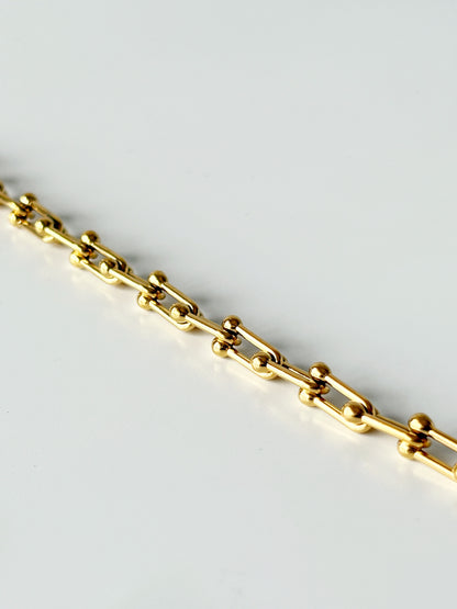 Gold chain bracelet on a light gray background