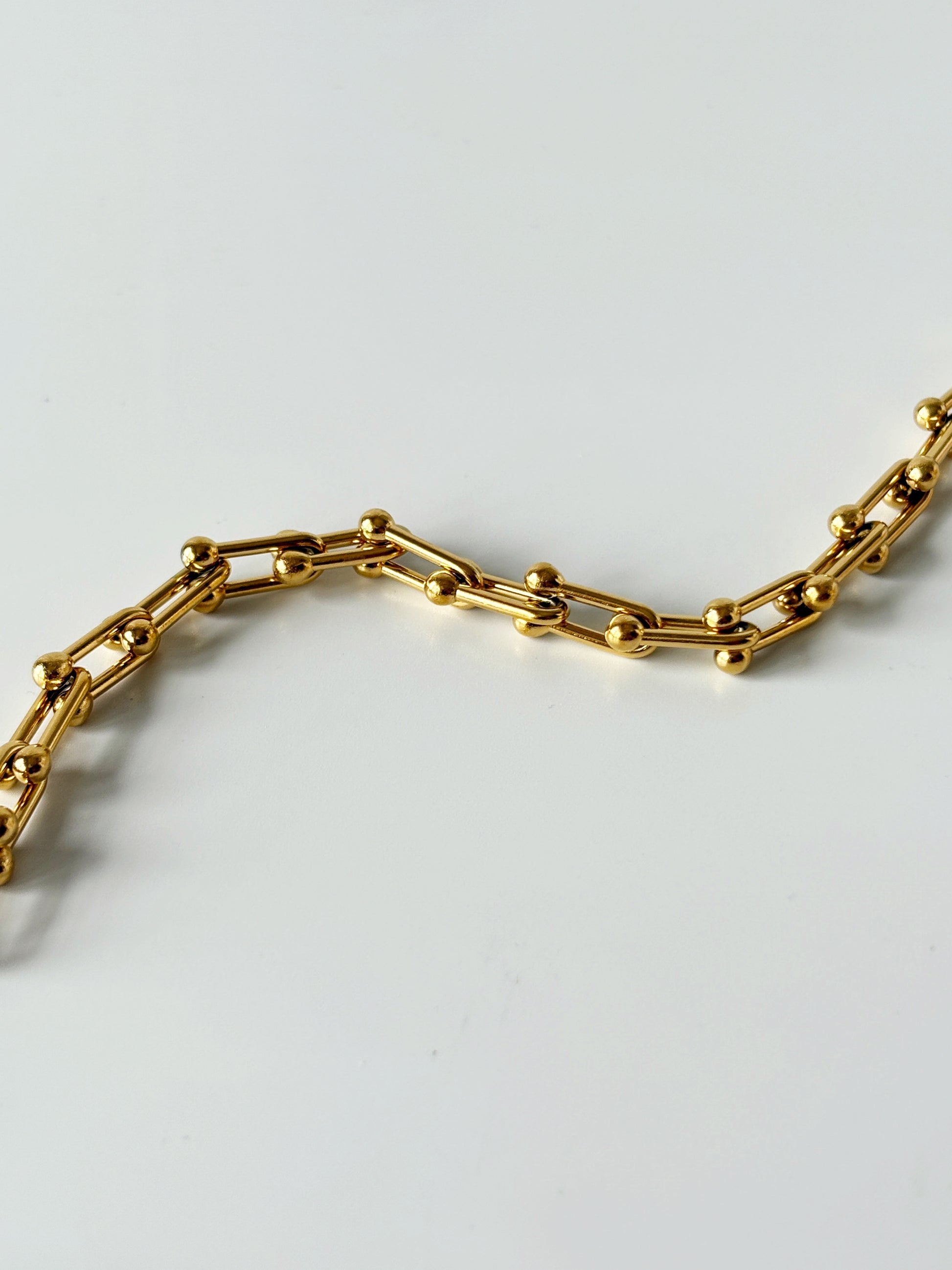 Gold chain bracelet on a light gray background