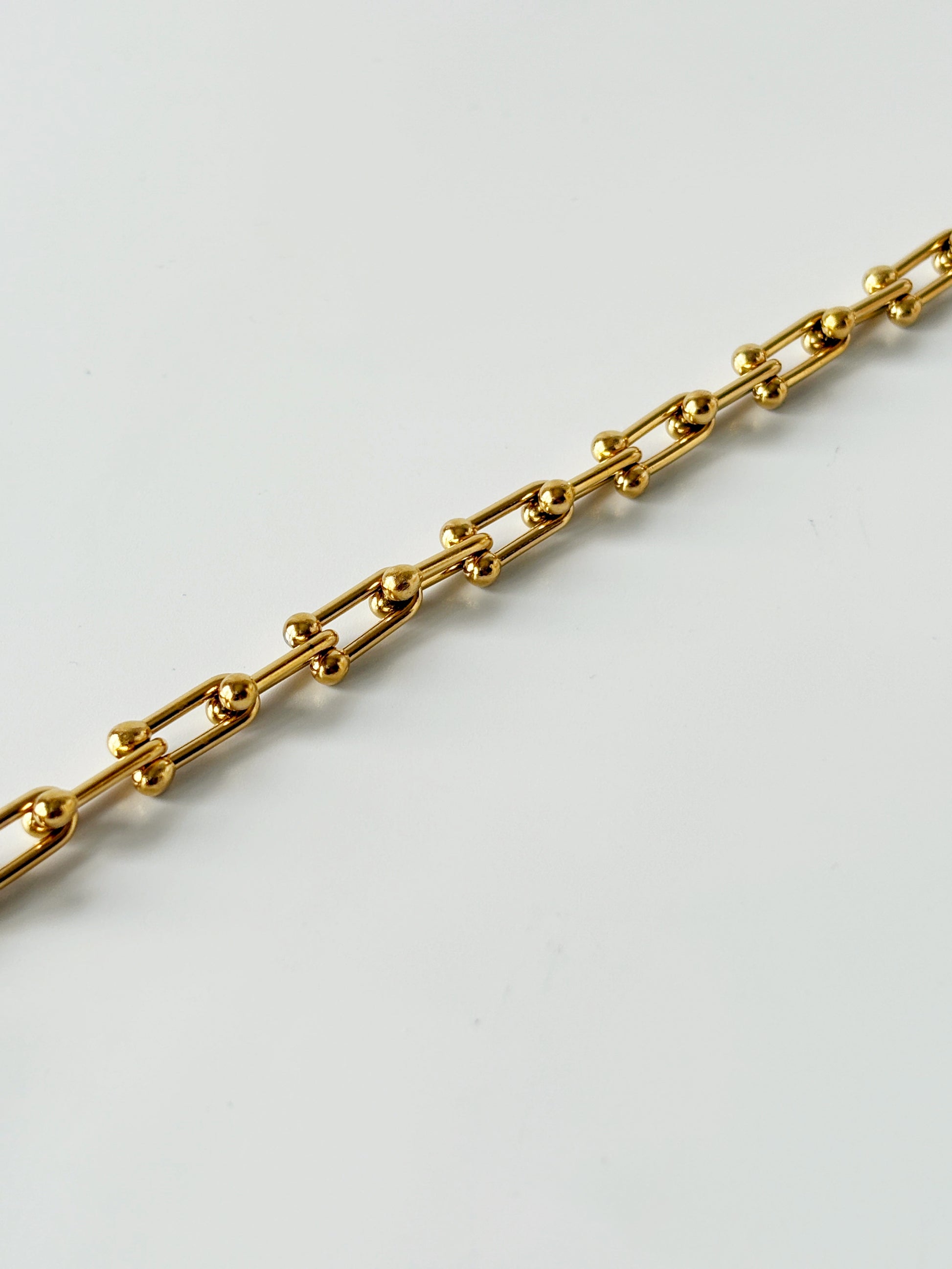 Gold chain bracelet on a light gray background