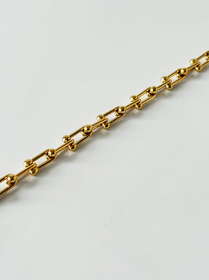 Gold chain bracelet on a light gray background