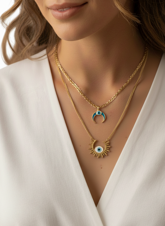 Woman wearing a 2-layered gold necklace with a blue pendant and a sun design.