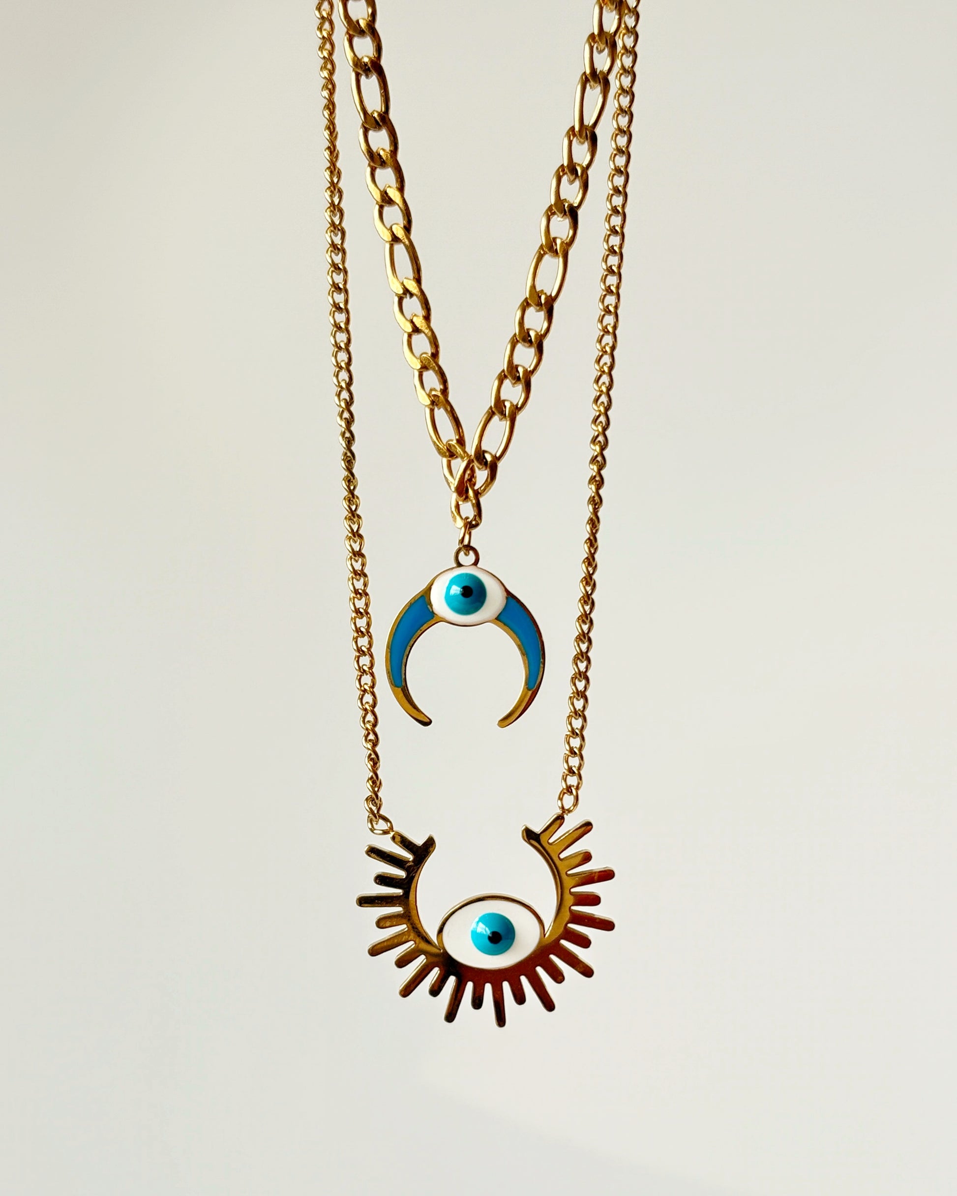 Two-layered Necklace with eye-shaped pendant and crescent moon pendant on a light gray background