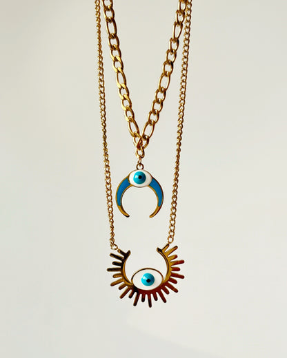 Two-layered Necklace with eye-shaped pendant and crescent moon pendant on a light gray background