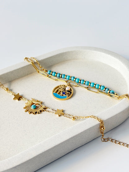 Gold and turquoise beaded bracelets on a white dish